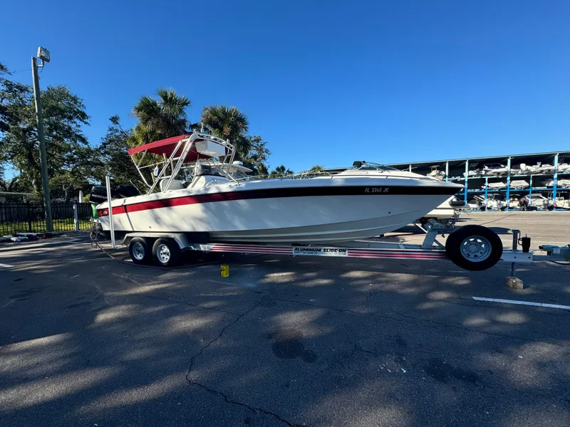 Slide: The Image of 1997 Wellcraft 302 boat on trailer, parked outdoors under clear blue sky. - 0