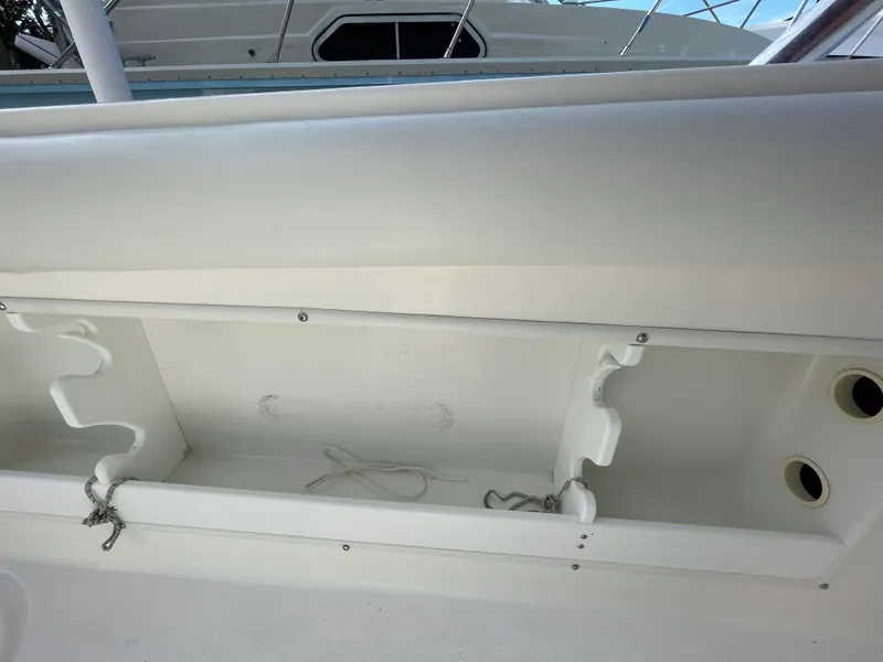 Slide: The Image of Storage compartment on a 1997 Wellcraft 302 boat, featuring white interior and hooks. - 12