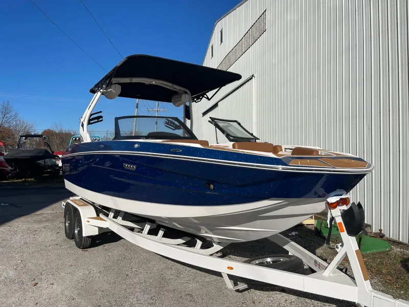 Slide: The Image of 2024 Supreme S220 boat with blue hull on trailer, parked outdoors. - 16