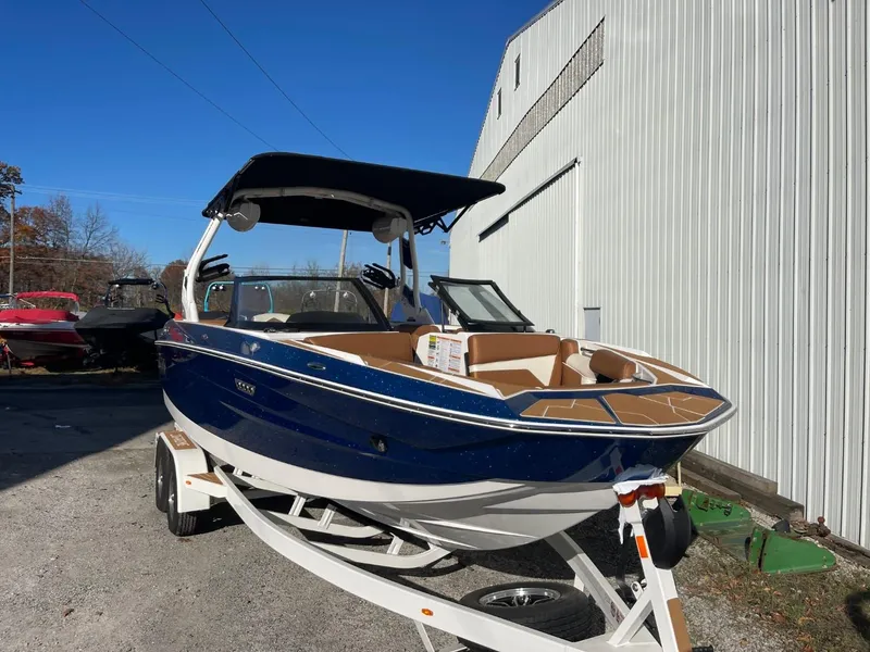 Slide: The Image of 2024 Supreme S220 boat, blue and white, on trailer near a warehouse. - 17