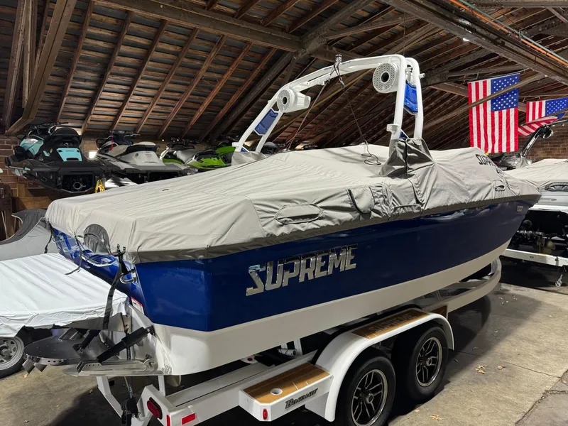 Slide: The Image of 2024 Supreme S220 boat covered in storage, blue and white design, on a trailer. - 18