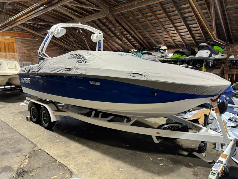 Slide: The Image of 2024 Supreme S220 boat covered in storage, blue hull, on a trailer. - 19