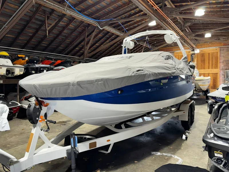 Slide: The Image of 2024 Supreme S220 boat covered in storage, blue and white hull, on a trailer. - 26