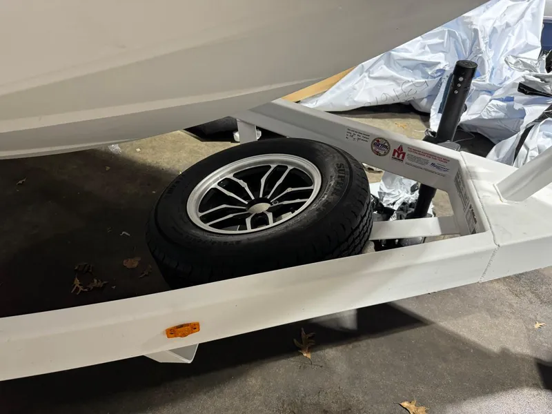 Slide: The Image of 2024 Supreme S220 boat trailer with spare tire, parked indoors. - 27