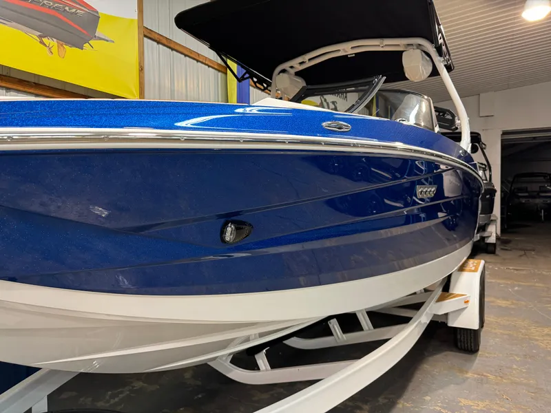 Slide: The Image of 2024 Supreme S220 boat in blue, displayed indoors on a trailer. - 33