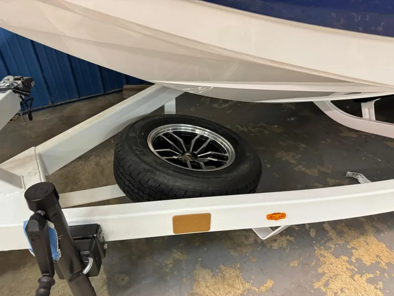 Slide: The Image of 2024 Supreme S220 boat trailer with spare tire, white frame, and blue hull. - 42
