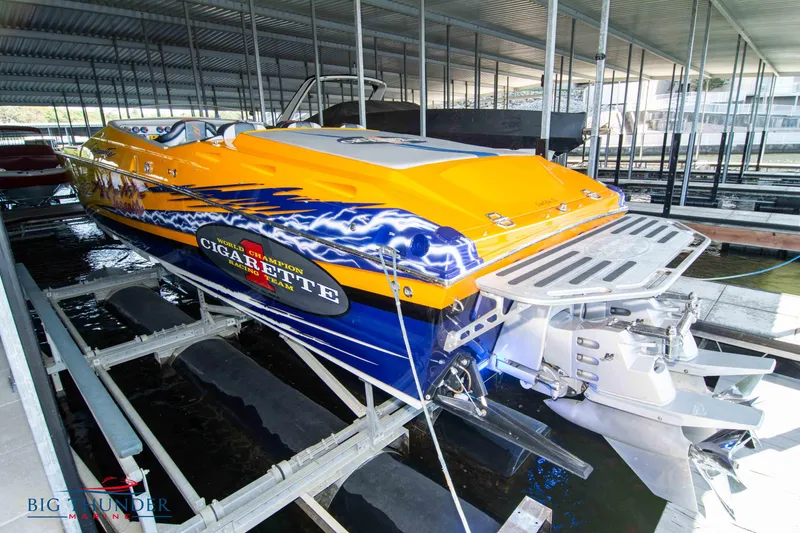 Slide: The Image of 2007 Cigarette 42X powerboat with vibrant orange and blue design in a marina. - 3