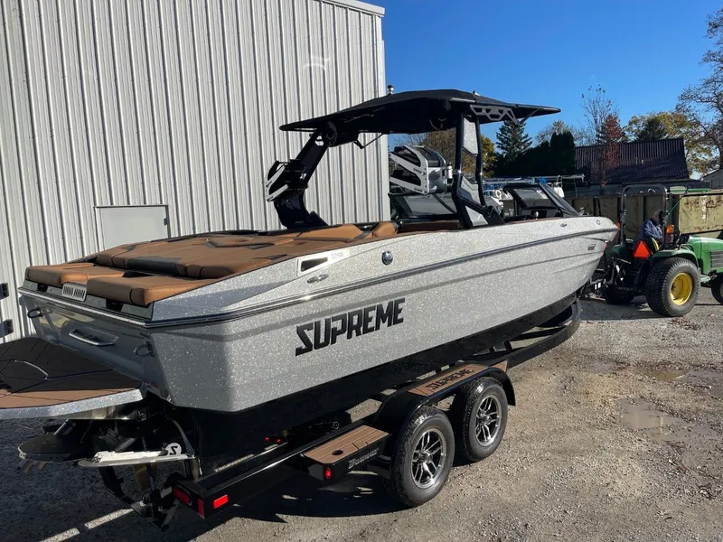 Slide: The Image of 2024 Supreme S240 boat on trailer, parked outdoors near a building. - 14