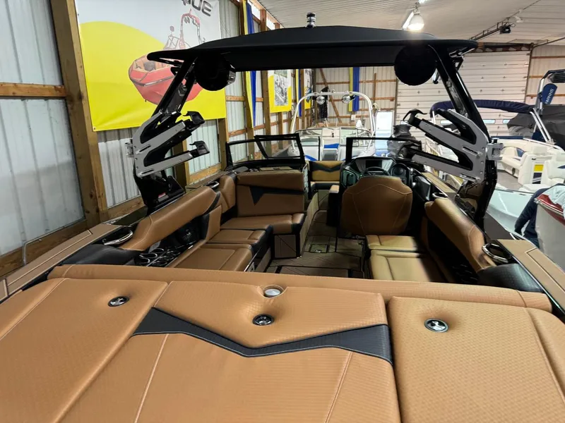 Slide: The Image of 2024 Supreme S240 boat interior with tan upholstery and sleek design in a showroom. - 22