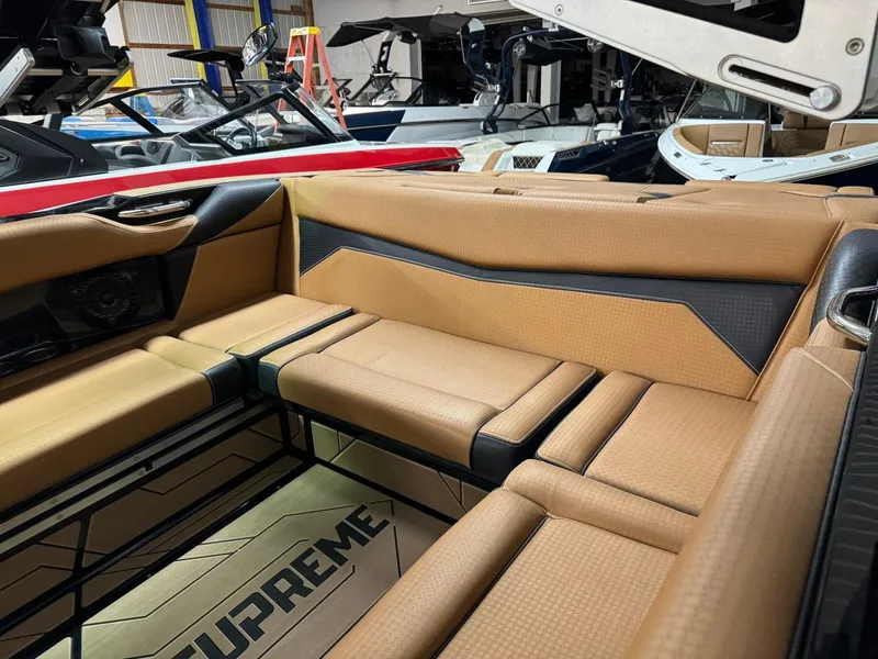 Slide: The Image of 2024 Supreme S240 boat interior with tan and black seating in a showroom. - 32