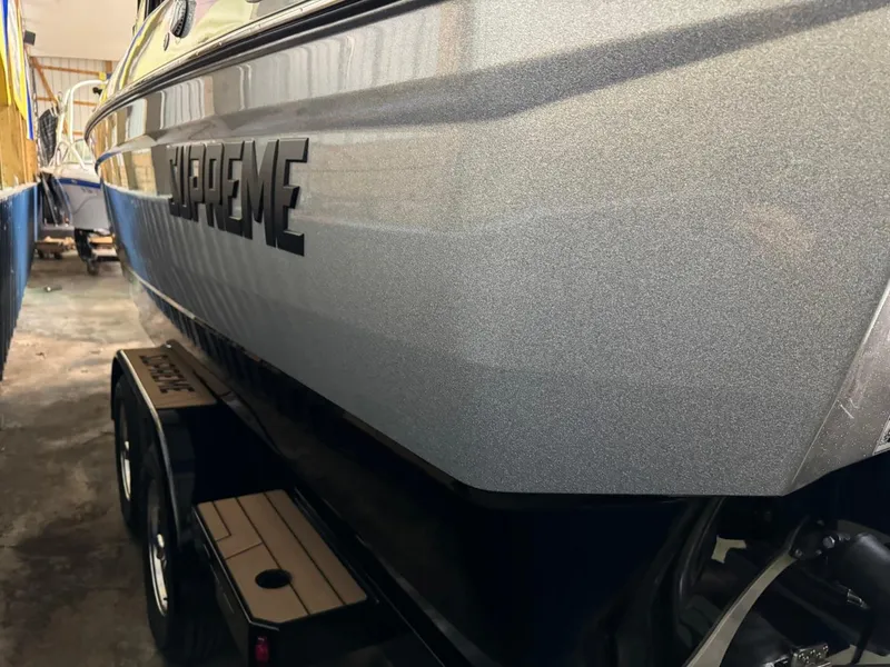 Slide: The Image of 2024 Supreme S240 boat side view in storage, showcasing sleek design and trailer. - 34