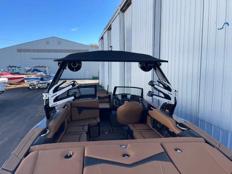 Slide: The Image of 2024 Supreme S240 boat with brown seating and black canopy, docked near warehouse. - 5