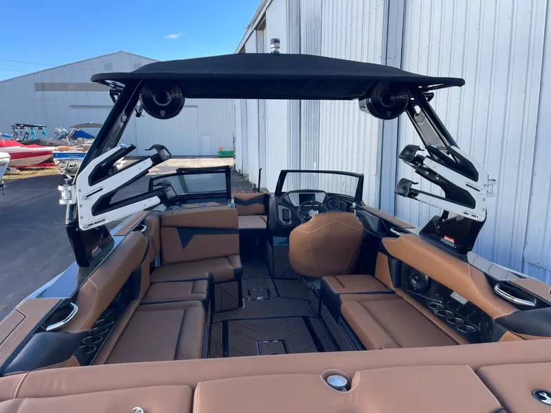 Slide: The Image of 2024 Supreme S240 boat interior with brown seating and black accents, docked near a warehouse. - 6