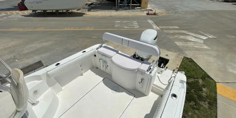 Slide: The Image of 2000 Cobia 220 Walkaround boat interior with seating and storage, parked on concrete. - 13