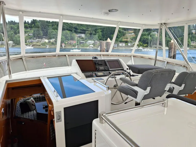 Slide: The Image of Pilothouse interior of 2004 Ocean Alexander 64, featuring helm and seating with scenic water view. - 24