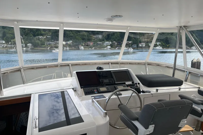 Slide: The Image of Pilothouse interior of 2004 Ocean Alexander 64, featuring navigation controls and scenic water view. - 26