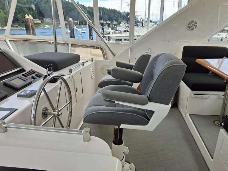 Slide: The Image of Pilothouse interior of 2004 Ocean Alexander 64, featuring helm, seating, and scenic marina view. - 29