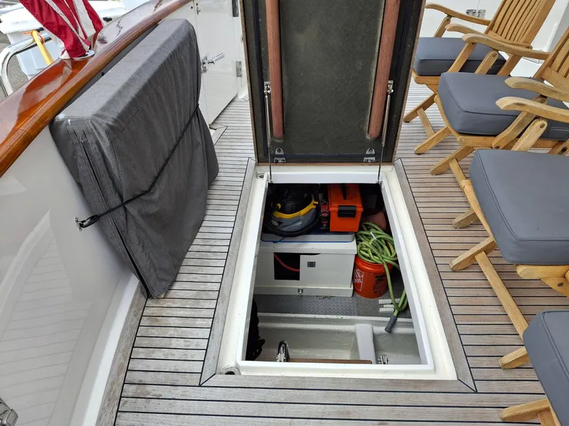 Slide: The Image of Open hatch on 2004 Ocean Alexander 64 Pilothouse, revealing storage with equipment and chairs on deck. - 37