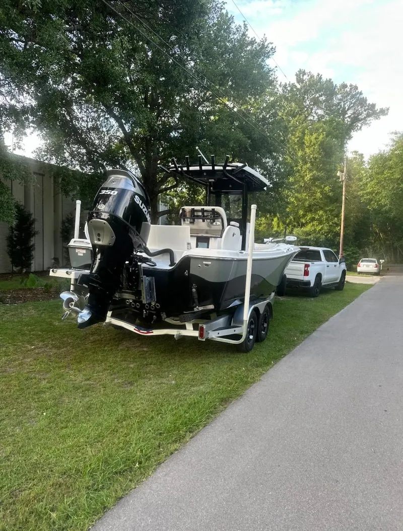 Slide: The Image of 2024 Blue Wave 2600 Makaira boat on trailer, parked beside a white truck. - 2