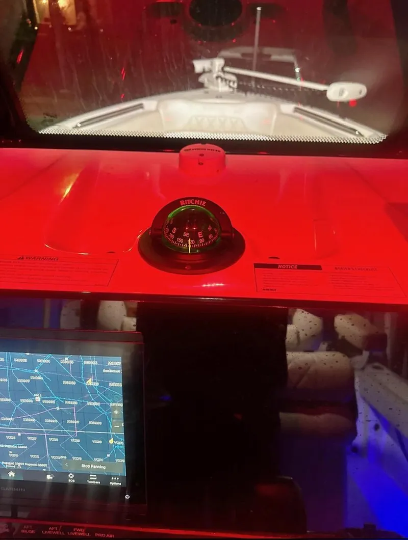 Slide: The Image of 2024 Blue Wave 2600 Makaira boat cockpit with compass and navigation screen at night. - 9