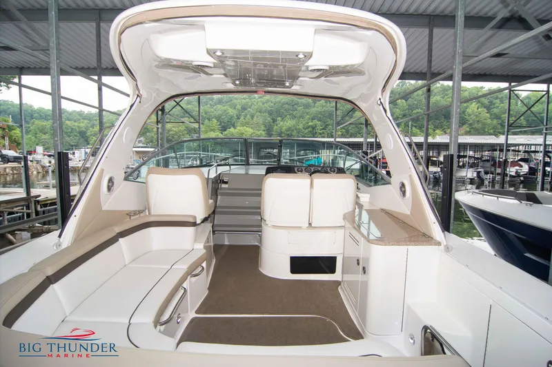 Slide: The Image of 2016 Sea Ray 370 Sundancer interior with seating and helm, docked at marina. - 14