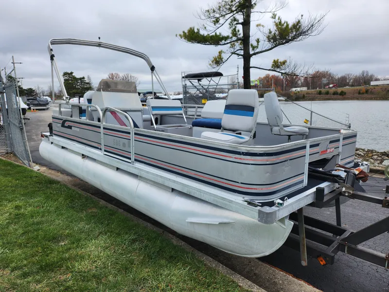 Slide: The Image of 1991 Grumman Fish N Fun 20' pontoon boat on trailer by a lake. - 8