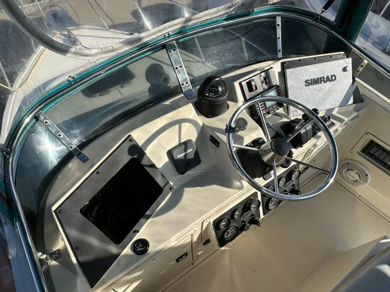 Slide: The Image of 1994 Precision 28 Convertible boat helm with steering wheel and Simrad navigation system. - 13