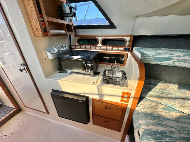 Slide: The Image of 1994 Precision 28 Convertible boat interior with kitchenette and seating area. - 19