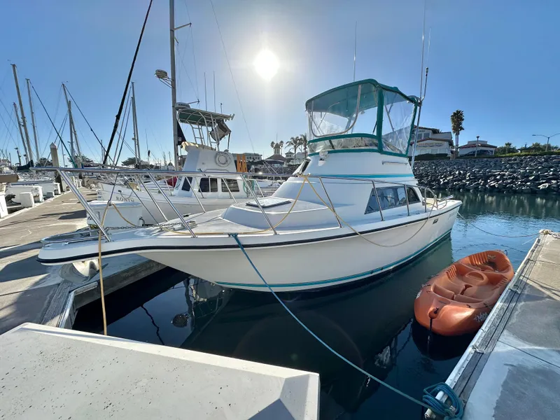 Slide: The Image of 1994 Precision 28 Convertible boat docked with kayak nearby, under clear sky. - 2