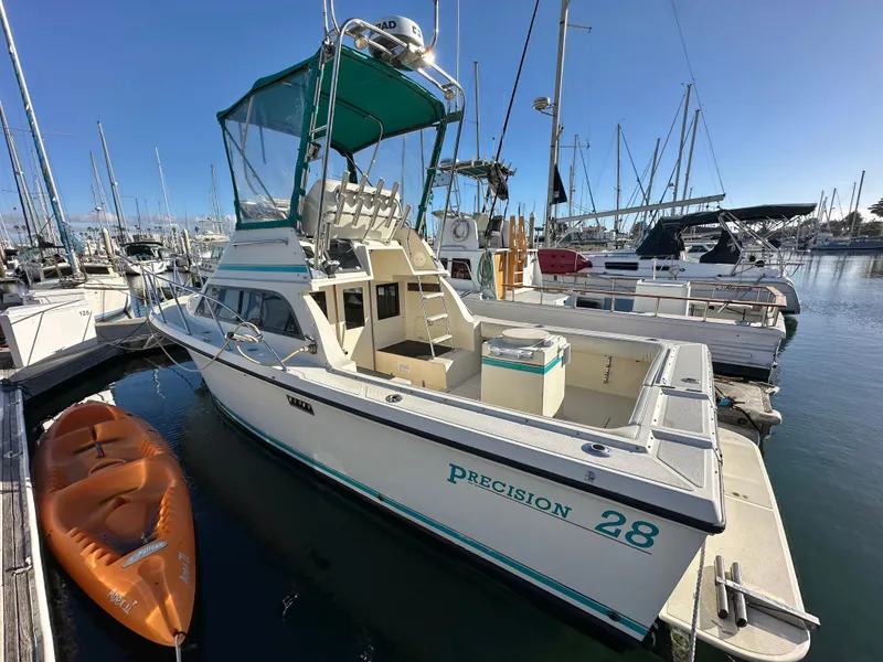 Slide: The Image of 1994 Precision 28 Convertible boat docked at marina, with kayak alongside. - 3