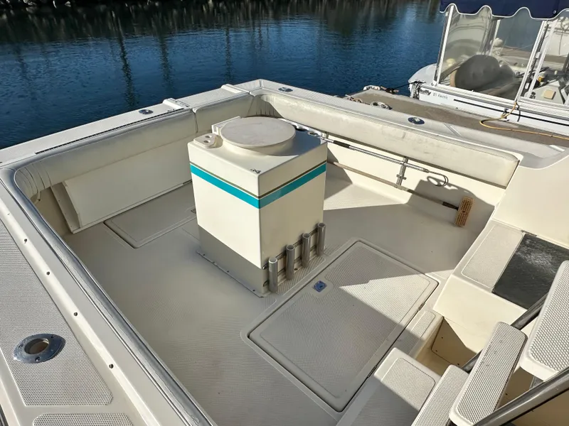 Slide: The Image of 1994 Precision 28 Convertible boat deck with seating and storage, docked by the water. - 5