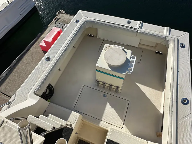 Slide: The Image of 1994 Precision 28 Convertible boat deck with central storage unit, docked at marina. - 7