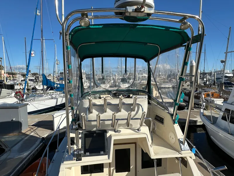 Slide: The Image of 1994 Precision 28 Convertible boat docked at marina, featuring green canopy and fishing rod holders. - 9