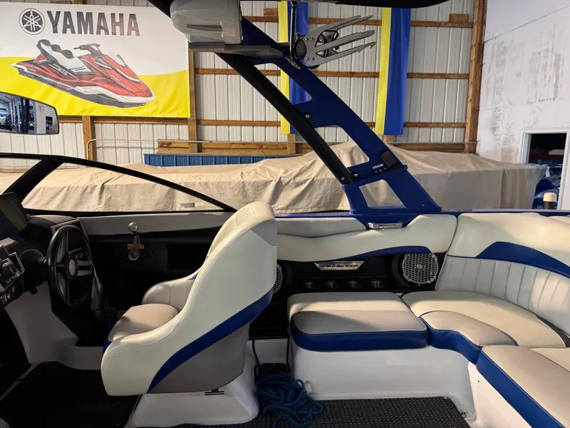 Slide: The Image of 2015 Malibu Wakesetter 22 MXZ interior with white and blue seating in a garage. - 12