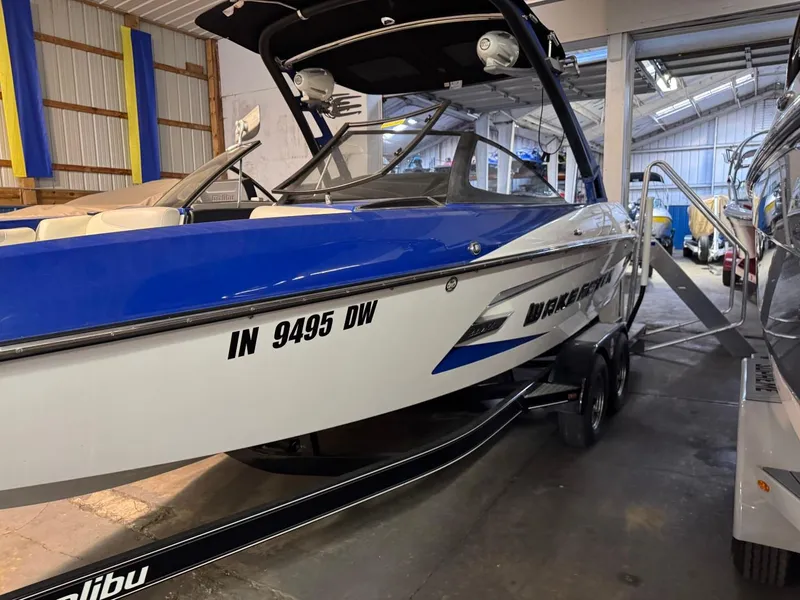 Slide: The Image of 2015 Malibu Wakesetter 22 MXZ boat in storage, blue and white exterior. - 15