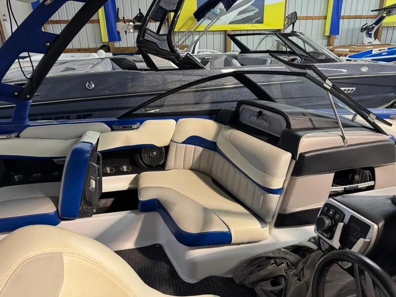 Slide: The Image of 2015 Malibu Wakesetter 22 MXZ interior with beige and blue seating in showroom. - 6