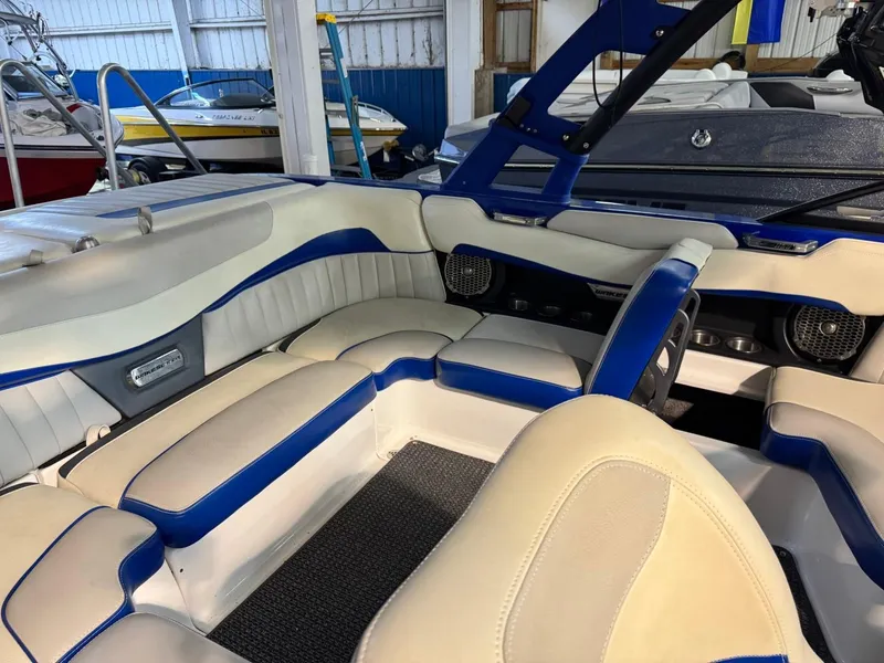Slide: The Image of 2015 Malibu Wakesetter 22 MXZ interior with blue and white seating in a showroom. - 7