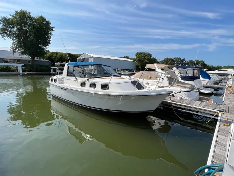 Slide: The Image of 1987 Carver Riviera 2807 boat docked in a marina under a clear blue sky. - 2