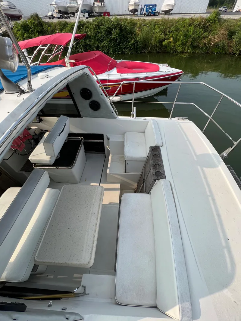 Slide: The Image of 1987 Carver Riviera 2807 boat interior with seating and table, docked near water. - 5