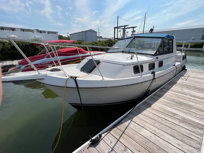 The Image of 1987 Carver Riviera 2807 boat docked at marina under clear sky. - 0