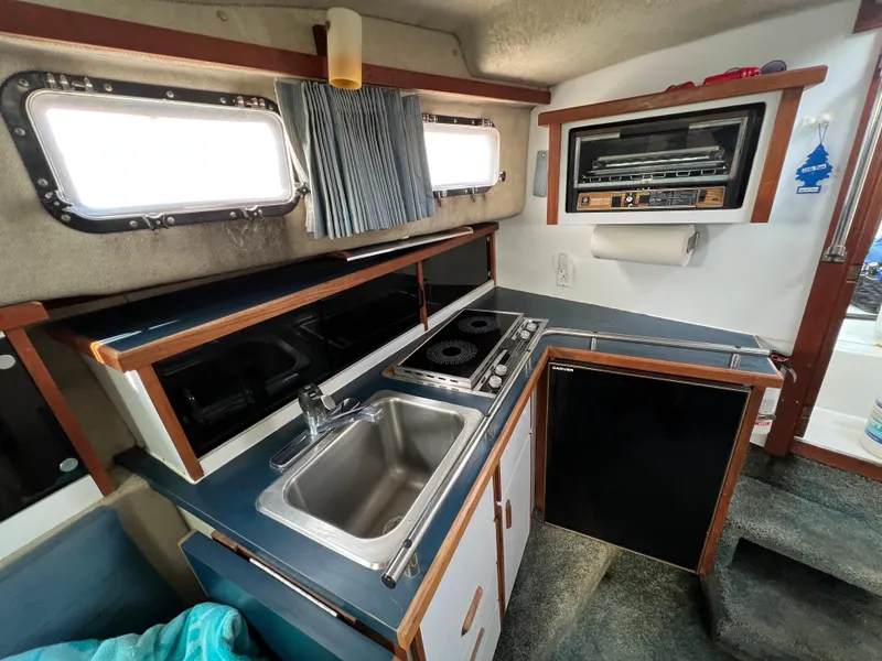 Slide: The Image of 1987 Carver Riviera 2807 boat kitchen with sink, stove, and storage cabinets. - 11
