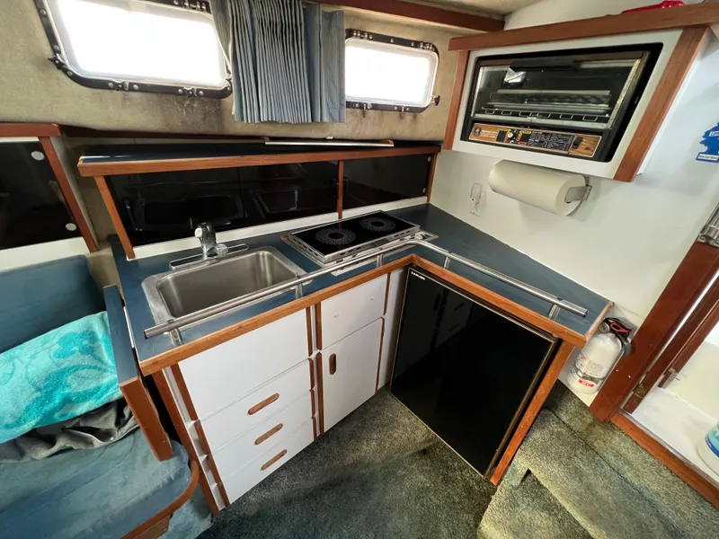Slide: The Image of 1987 Carver Riviera 2807 boat kitchen with sink, stove, and compact fridge. - 12