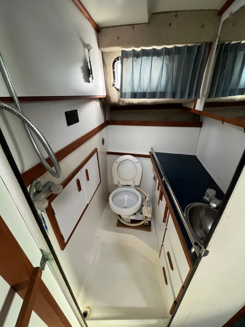 Slide: The Image of 1987 Carver Riviera 2807 boat bathroom with toilet, sink, and storage cabinets. - 16