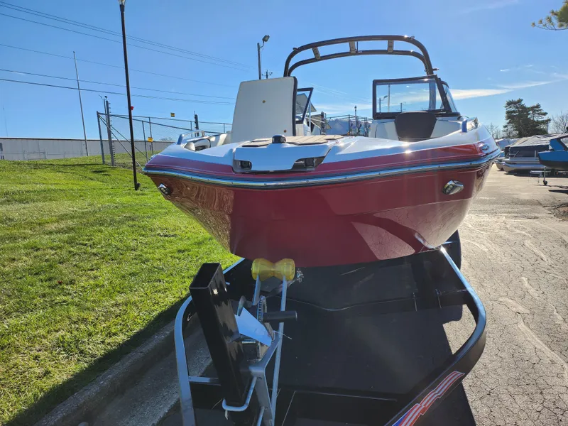 Slide: The Image of 2016 Yamaha Boats 242 Limited S on trailer, red hull, sunny day. - 6