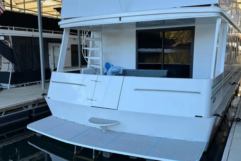 Slide: The Image of 1997 Lazy Days River Cruiser docked, featuring a spacious rear deck and ladder. - 23