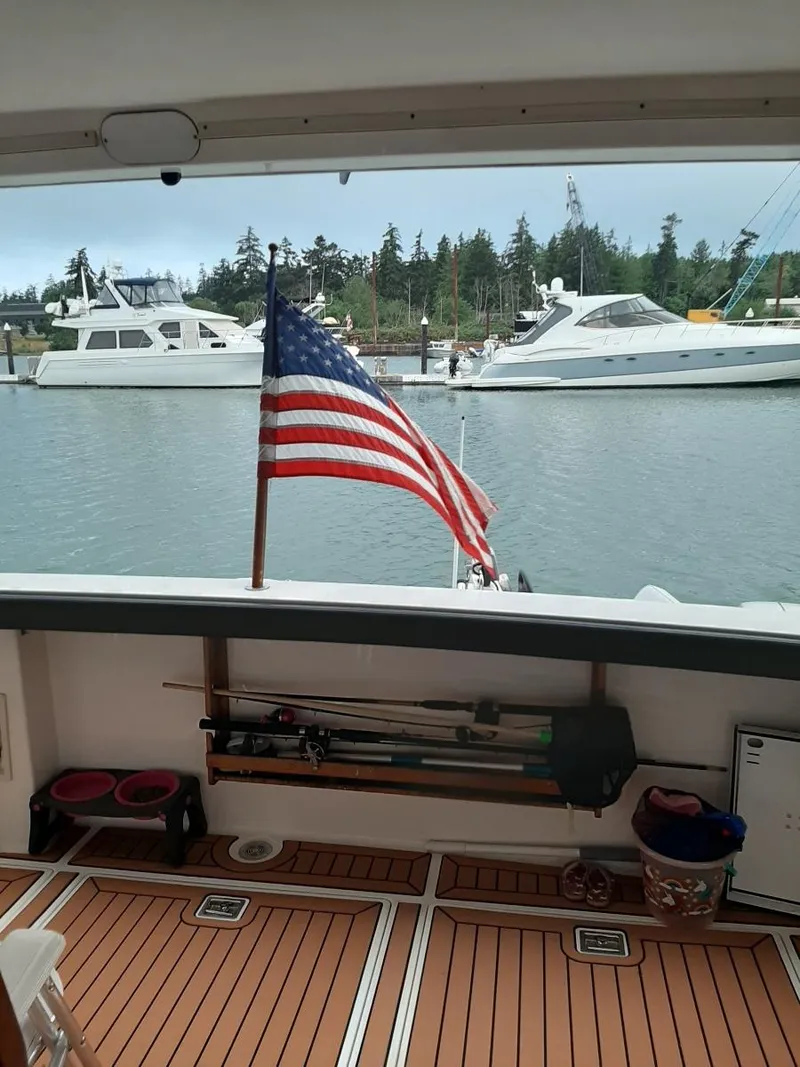 Slide: The Image of 1995 Bayliner 4788 Pilot House Motoryacht with American flag, docked in a marina. - 14