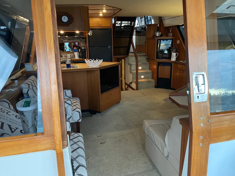 Slide: The Image of Interior of 1995 Bayliner 4788 Pilot House Motoryacht, featuring cozy seating and wooden cabinetry. - 16