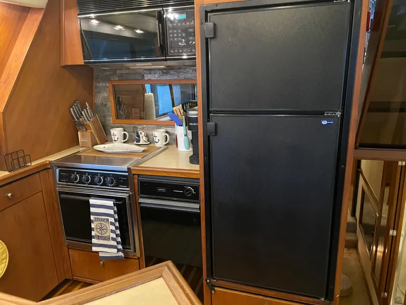 Slide: The Image of 1995 Bayliner 4788 Pilot House Motoryacht kitchen with stove, microwave, and refrigerator. - 24