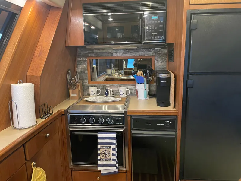 Slide: The Image of 1995 Bayliner 4788 Pilot House Motoryacht kitchen with stove, microwave, and refrigerator. - 25