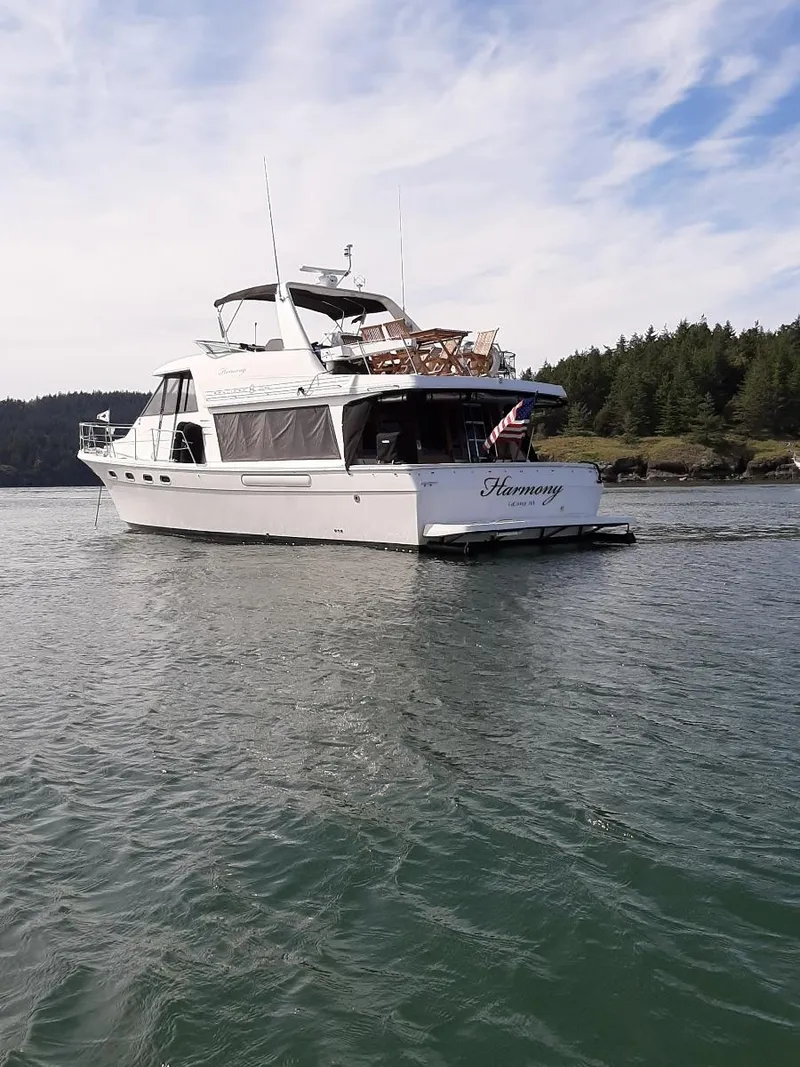 Slide: The Image of 1995 Bayliner 4788 Pilot House Motoryacht on serene water with forested shoreline. - 3